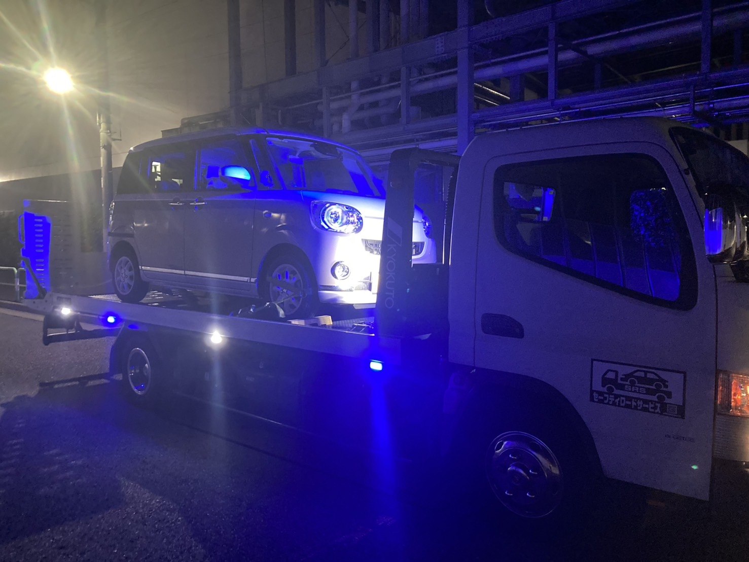 積載車に軽自動車を積み込んでいる夜間の作業写真