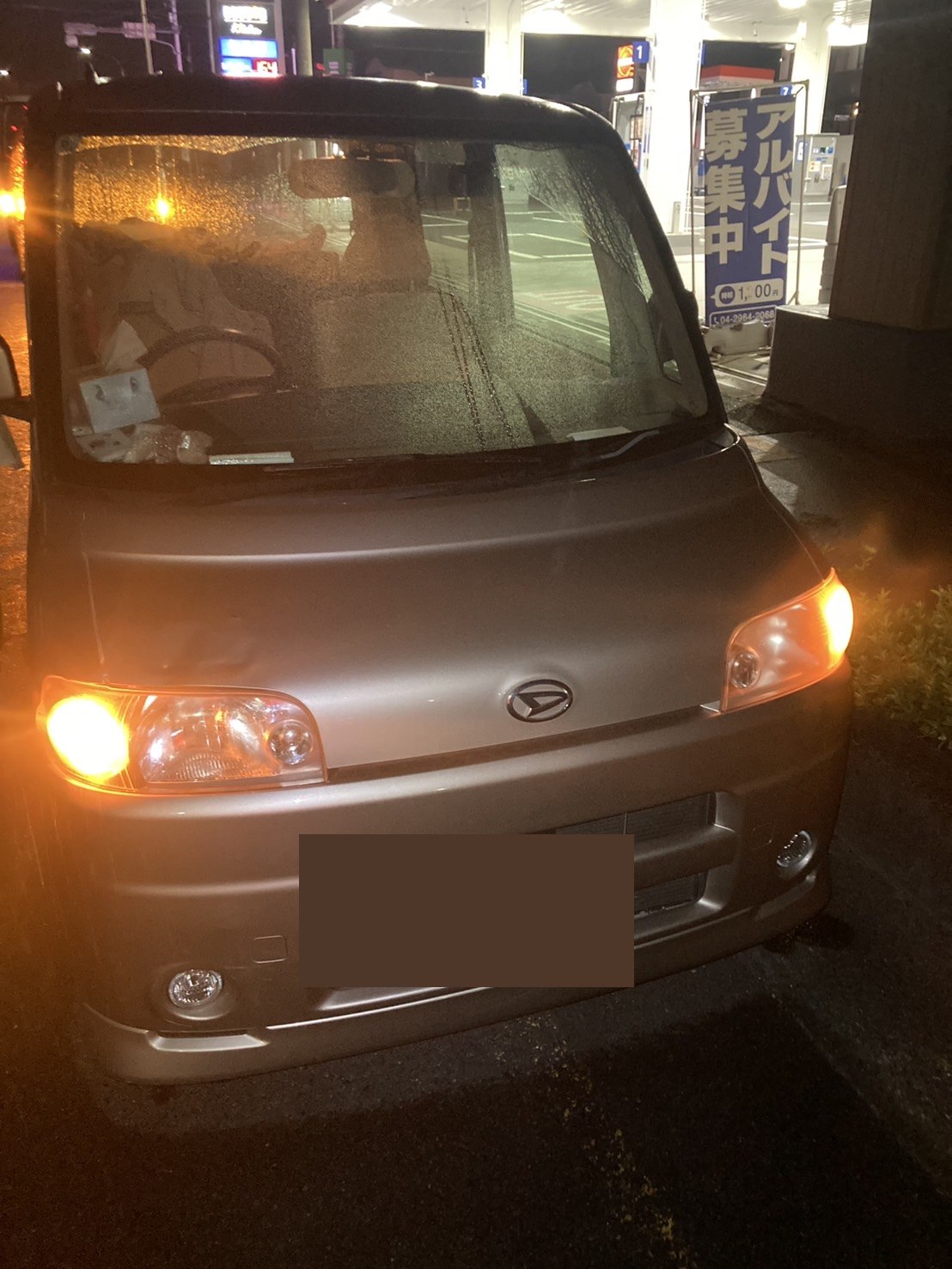 夜間の店舗前に停車した軽乗用車の正面