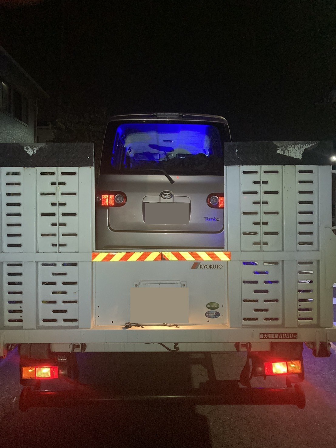 積載車の荷台に載せられた軽乗用車の後方