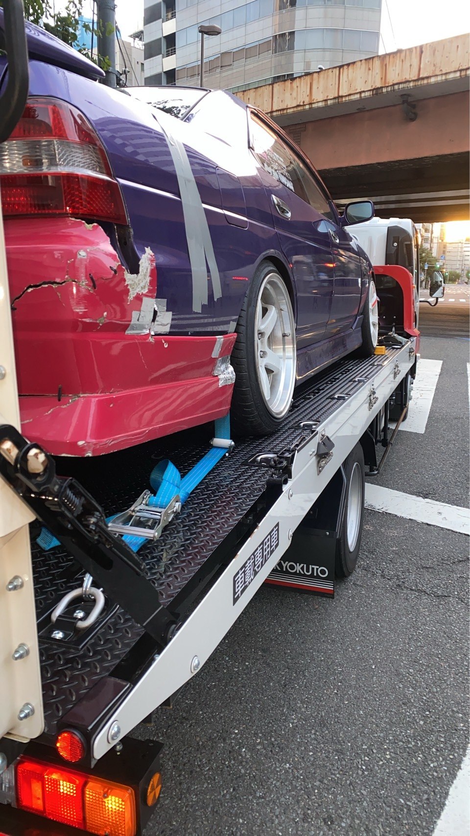積載車上で固定された車両の左後部と固定具