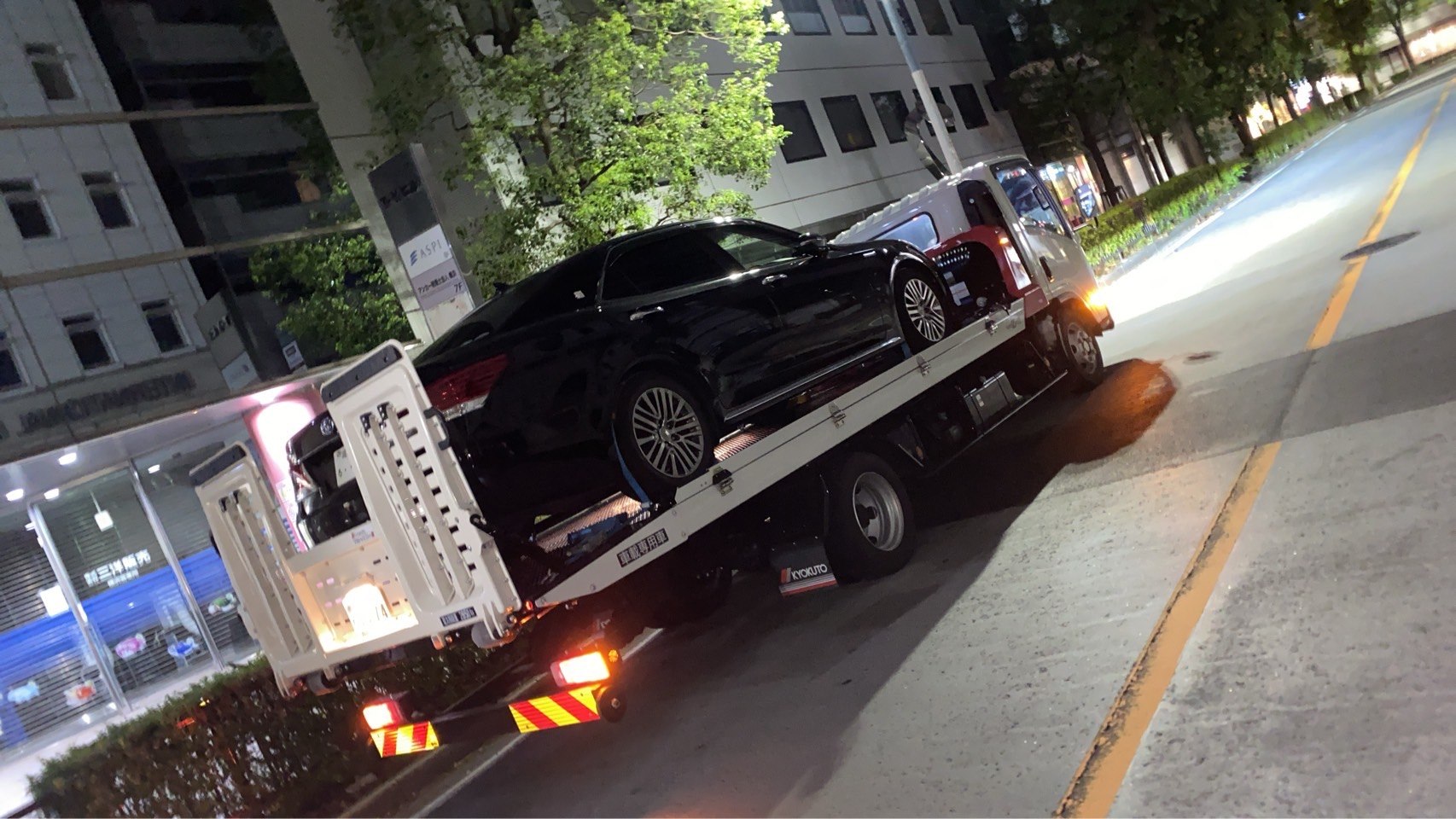 積載車に固定された黒色セダンを側方から撮影