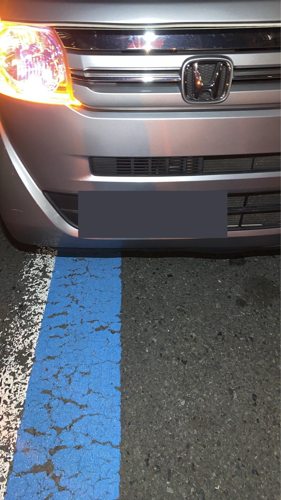 夜間に撮影されたシルバーの軽自動車前面の様子