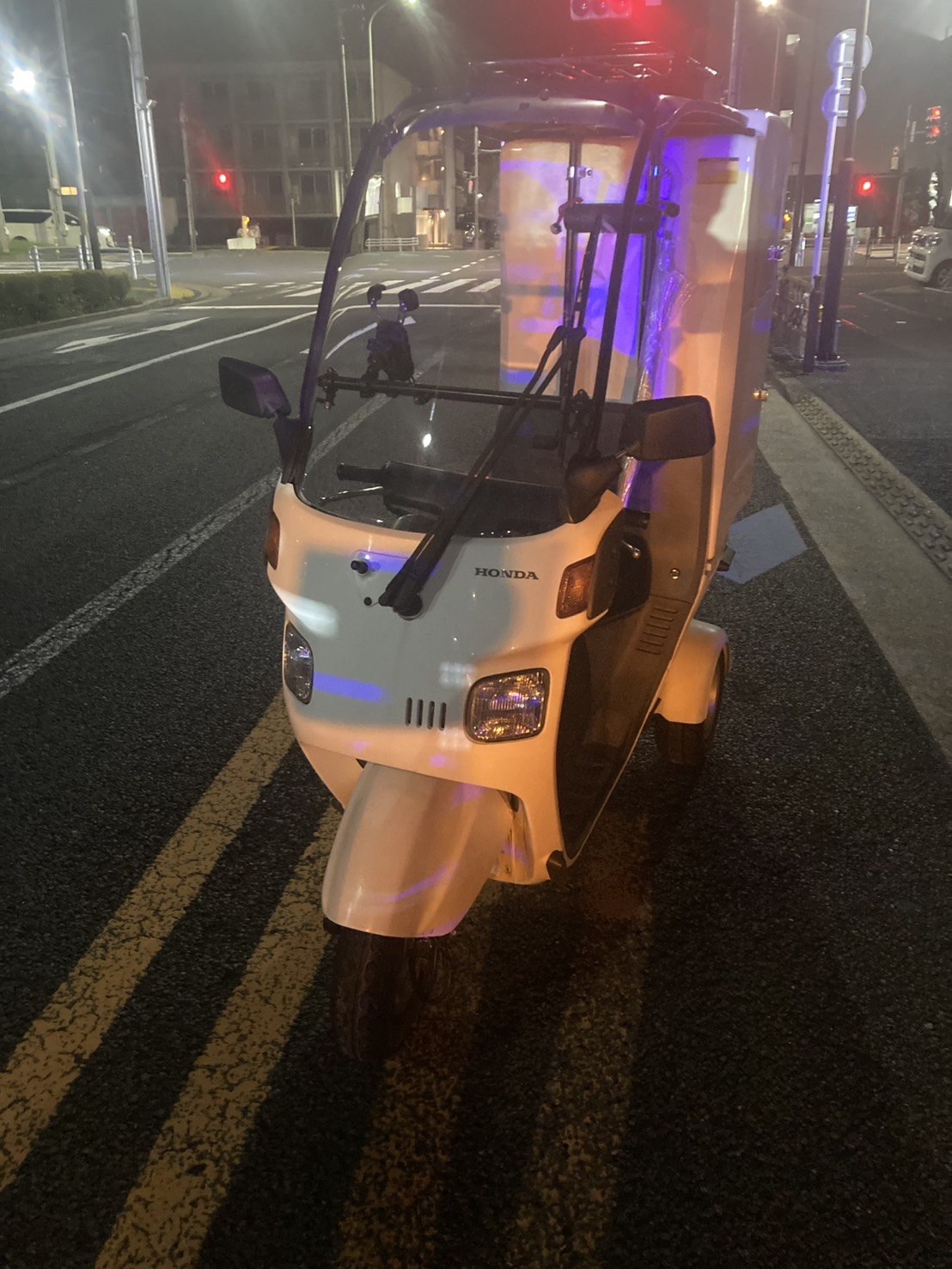 白い三輪スクーターの前方全景を夜間の路上で撮影