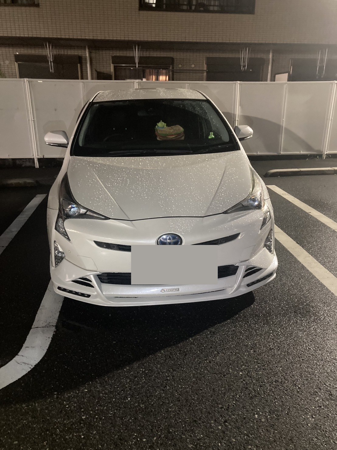 夜間の駐車場で撮影した白い対象車両の正面全景