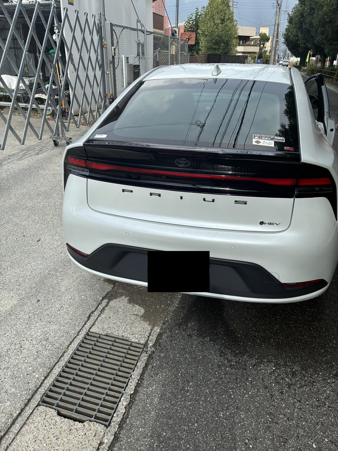 路上に停車した白いセダンの後部を撮影した様子