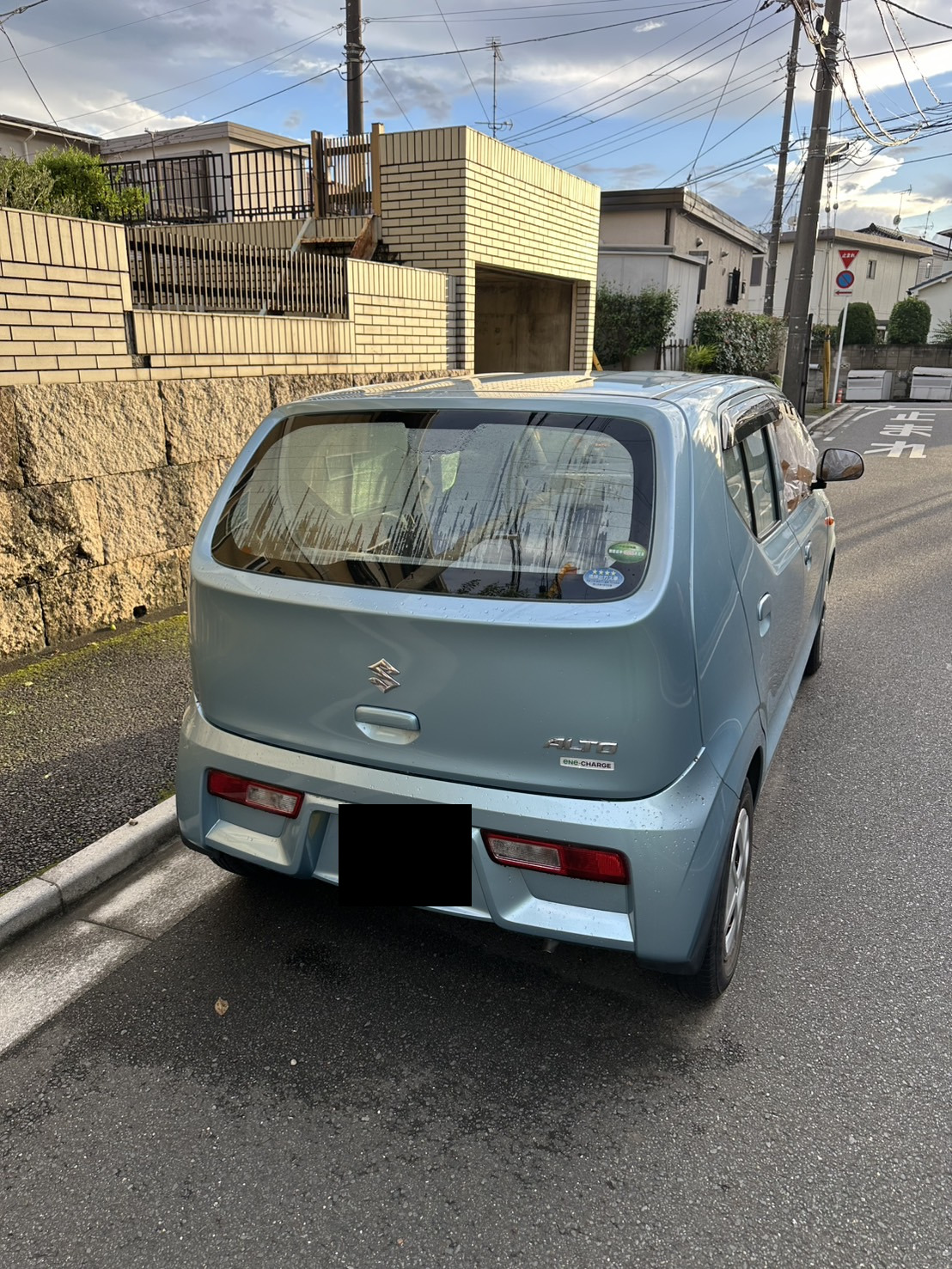 住宅街の路上に停車した水色の軽自動車を後方から見た様子
