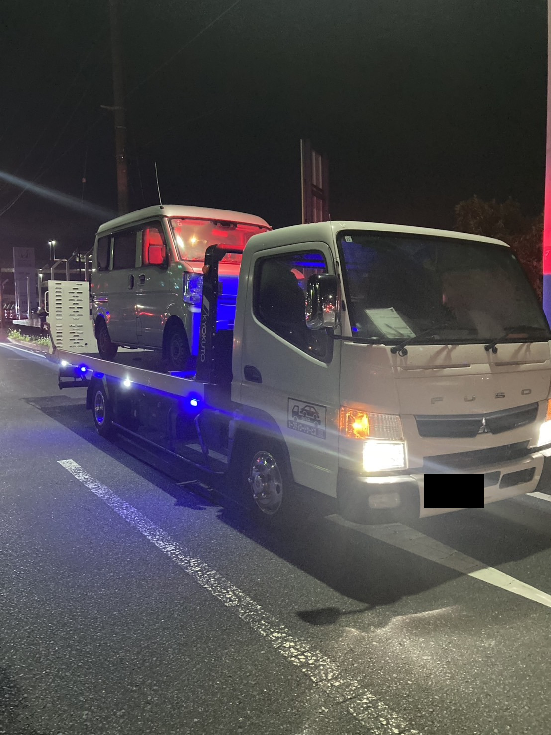 夜間の路上で軽バンを積載した積載車を横から見た様子