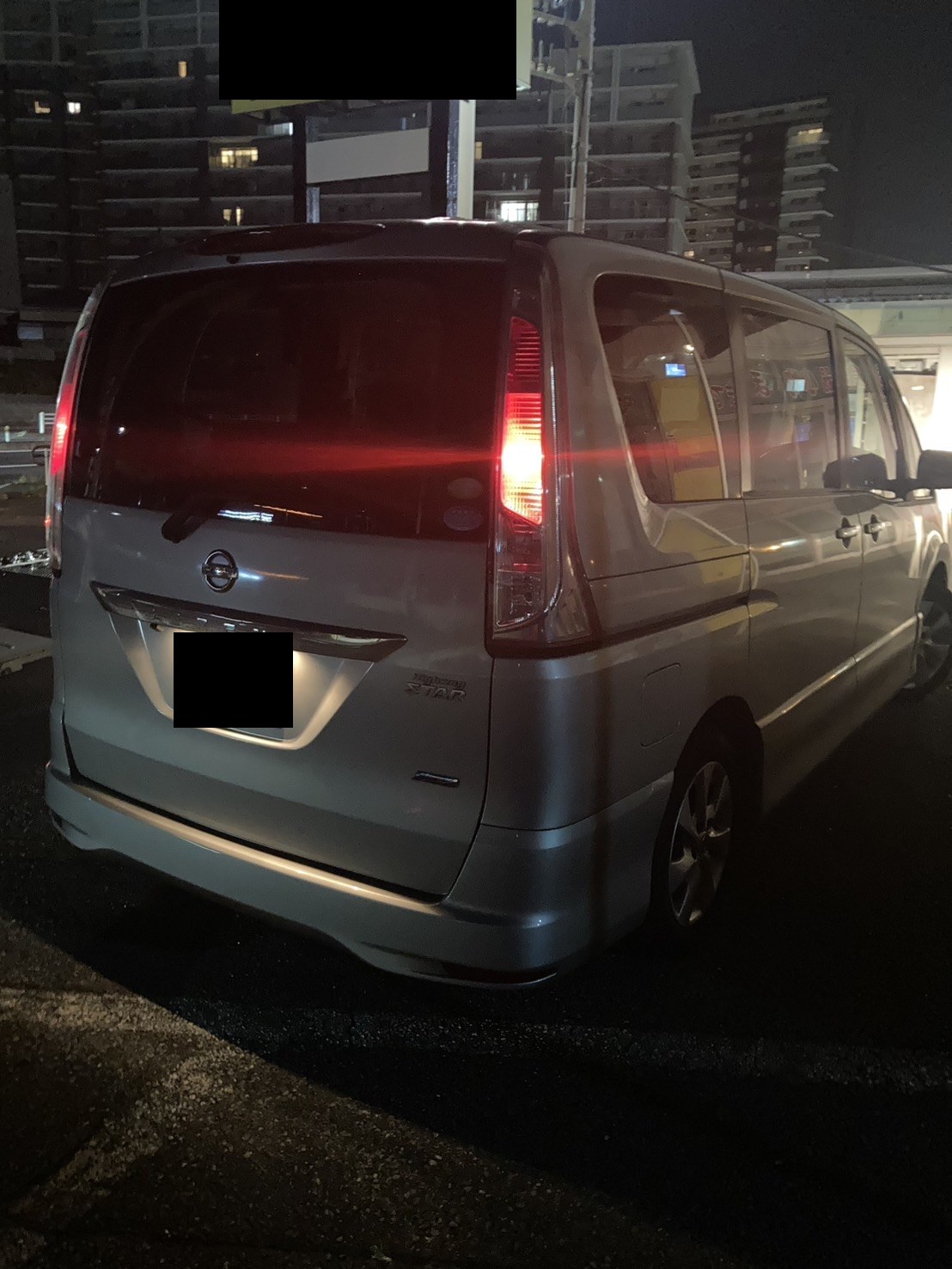 夜間、路上に停車したシルバーのミニバンを後方から見た様子（ナンバープレートはマスク処理）