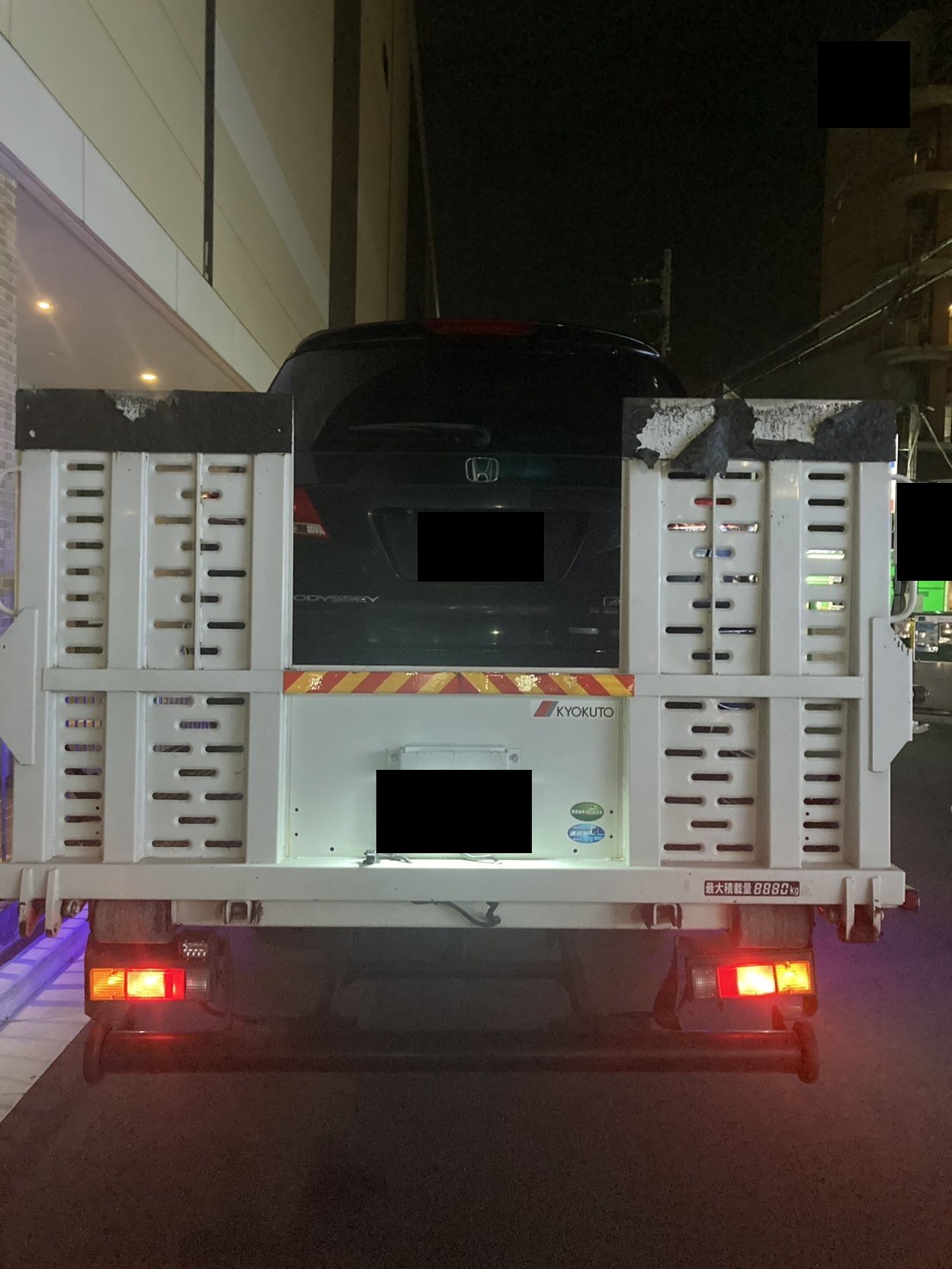 夜間、積載車に載せた黒いミニバンを後方から見た様子（ナンバープレートはマスク処理）