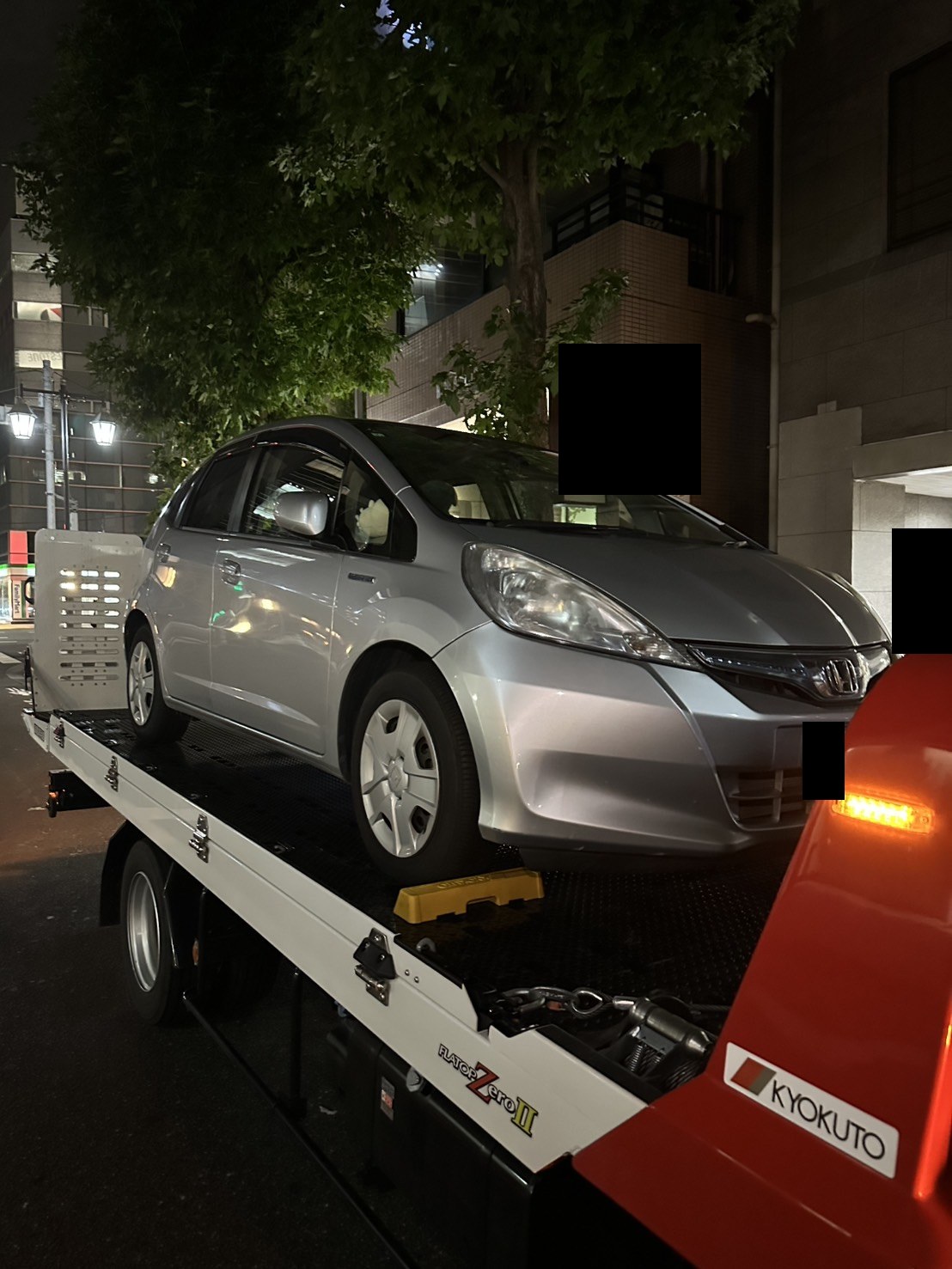 積載車の荷台に載せた車両を前方側面から見た様子（ナンバープレートはマスク処理）