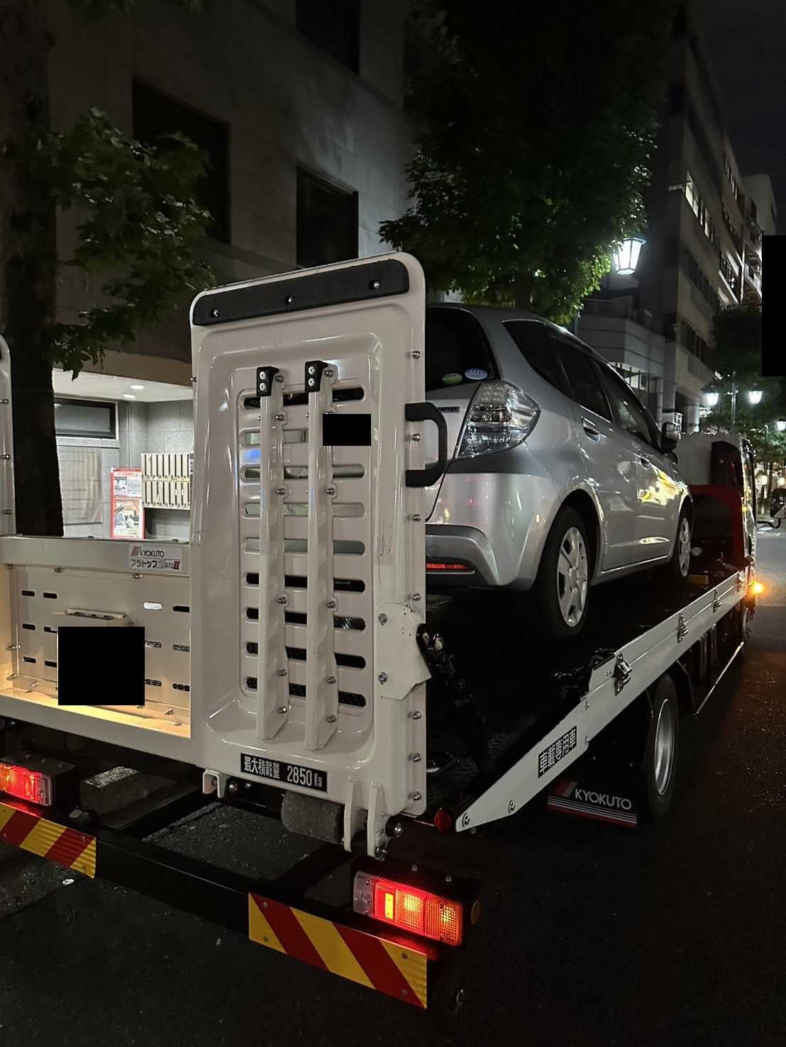積載車の後方から見た荷台と搬送車両の様子（ナンバープレートはマスク処理）