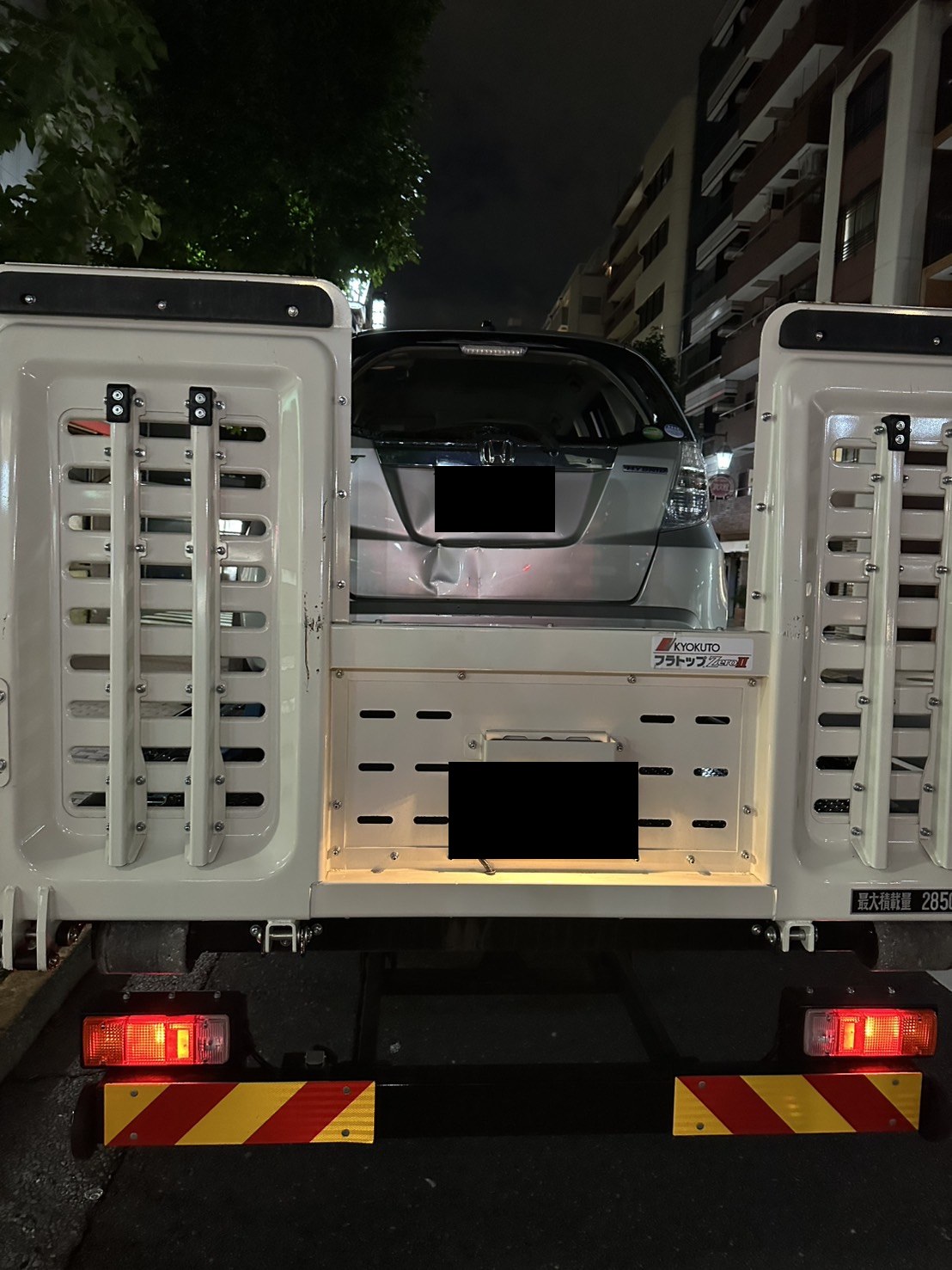 積載車の荷台に固定された車両後部の様子（ナンバープレートはマスク処理）