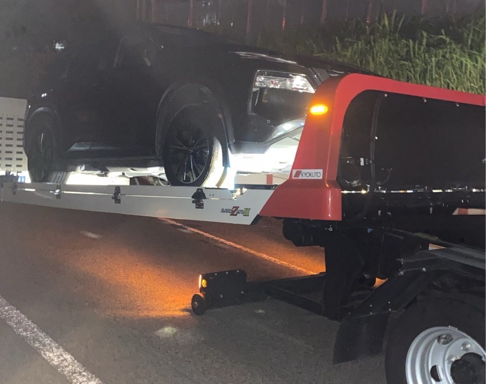 夜間、積載車の荷台に載せたSUVを後方から見た様子