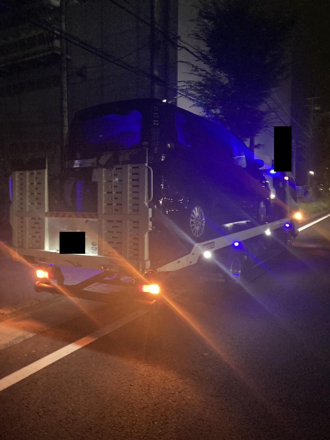 夜間の道路上で積載車に車両を載せ終えた様子（ナンバープレートはマスク処理）