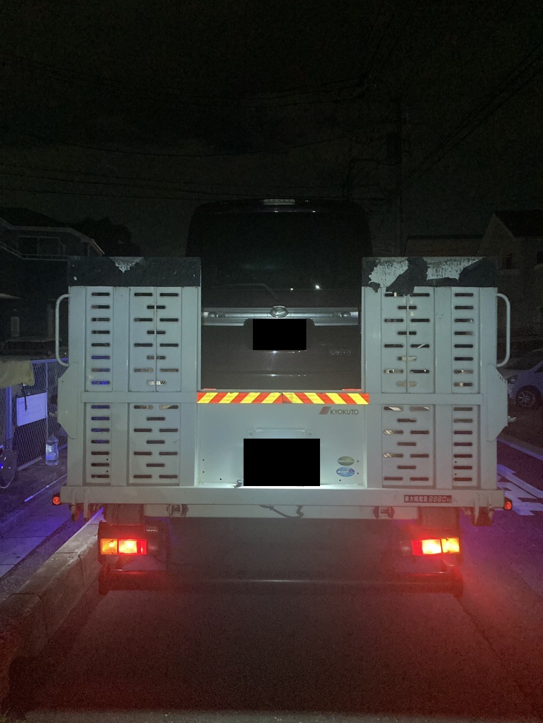 積載車の荷台に固定された軽ワゴンを後方から見た様子（ナンバープレートはマスク処理）