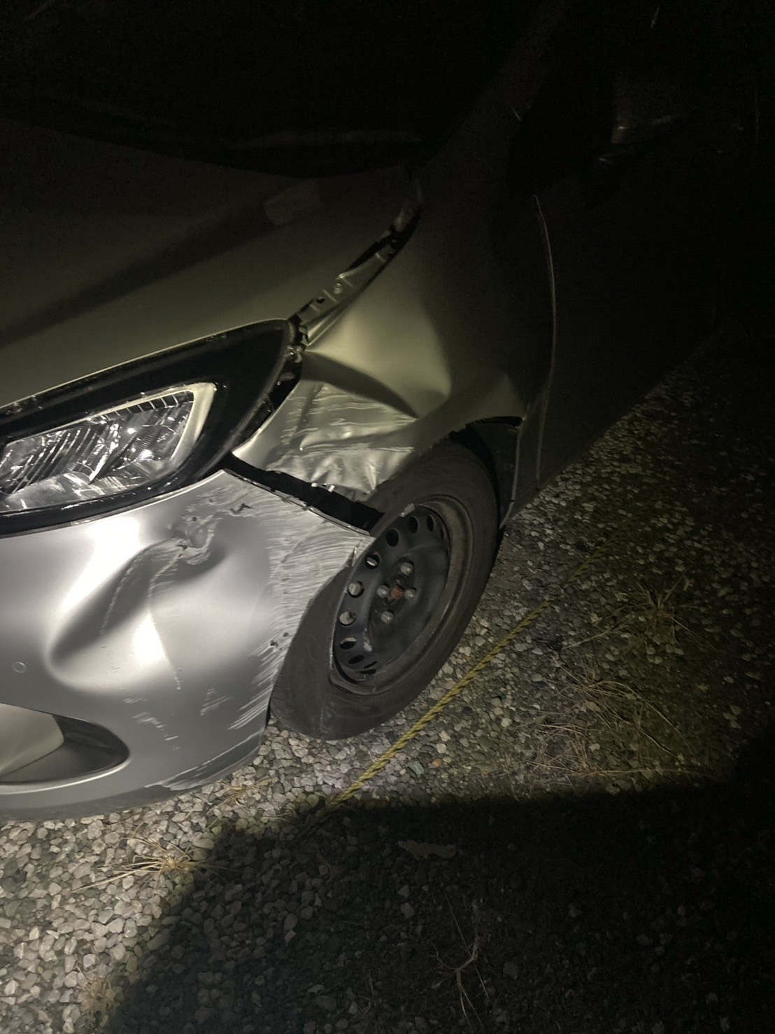 左前のフェンダーとバンパーが変形し、タイヤハウスが損傷したコンパクトカーの左前部