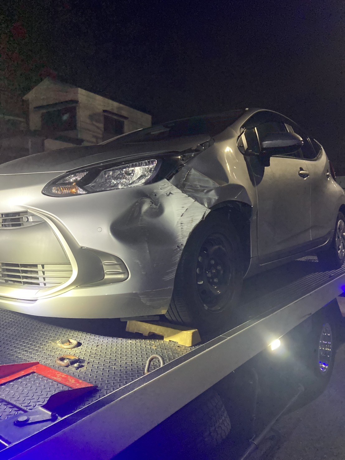 積載車の荷台に載せた損傷したコンパクトカーを左前方から見た様子