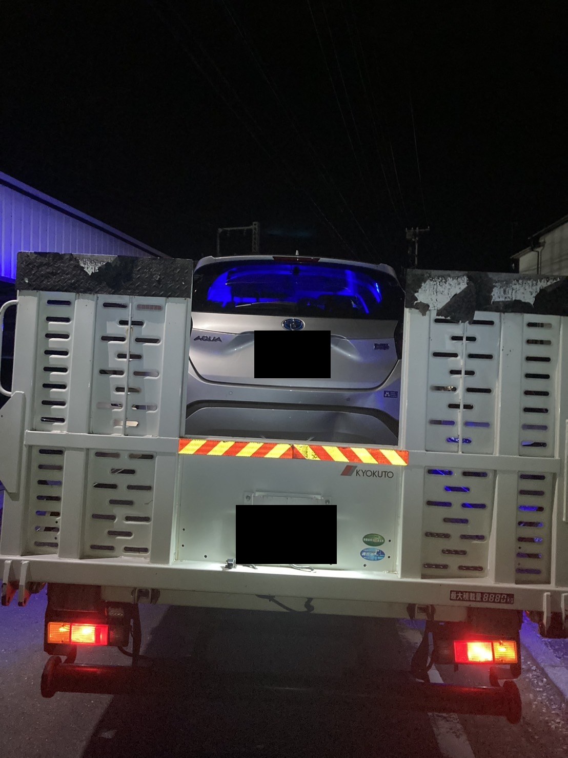積載車の荷台に固定されたコンパクトカーを後方から見た様子（お車と積載車のナンバープレートはマスク処理）