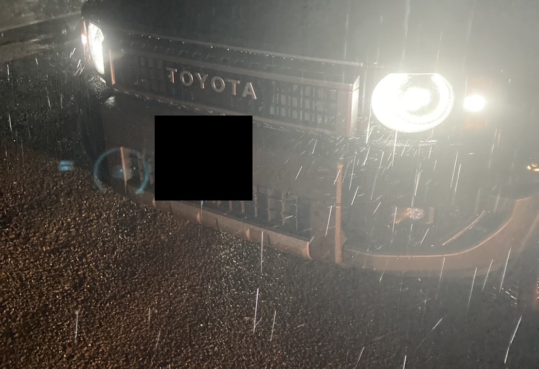 雨の夜、停車したSUVを正面から見た様子（ナンバープレートはマスク処理）