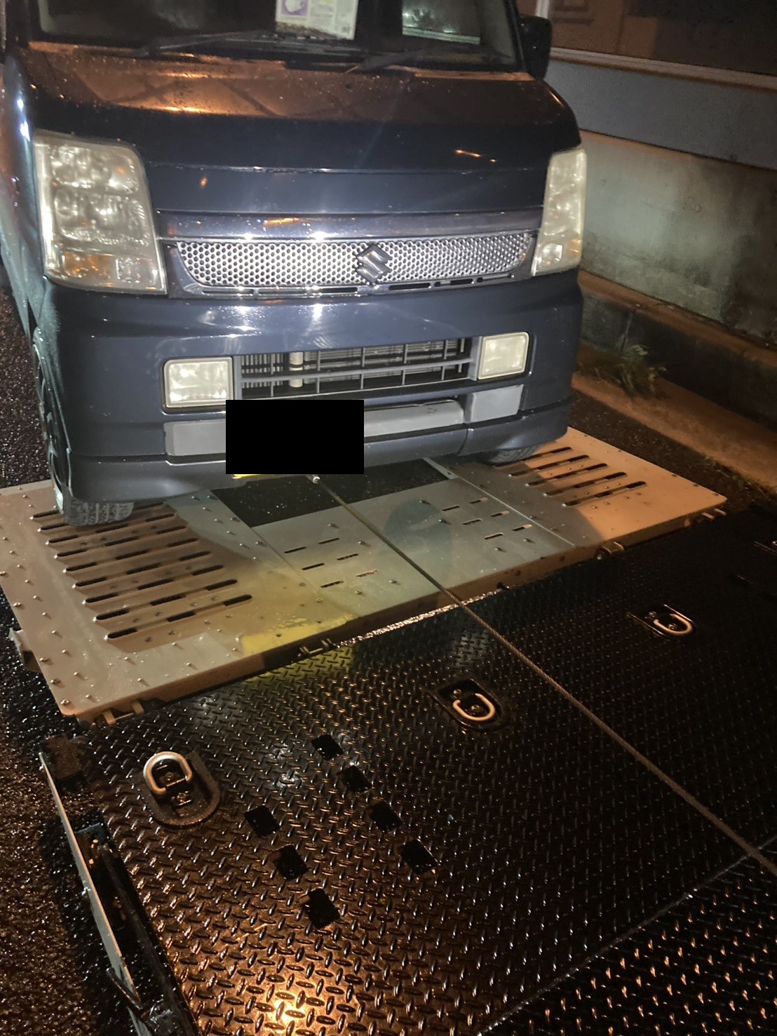 積載車のスロープに前輪を載せた軽ワゴンを正面から見た様子（ナンバープレートはマスク処理）