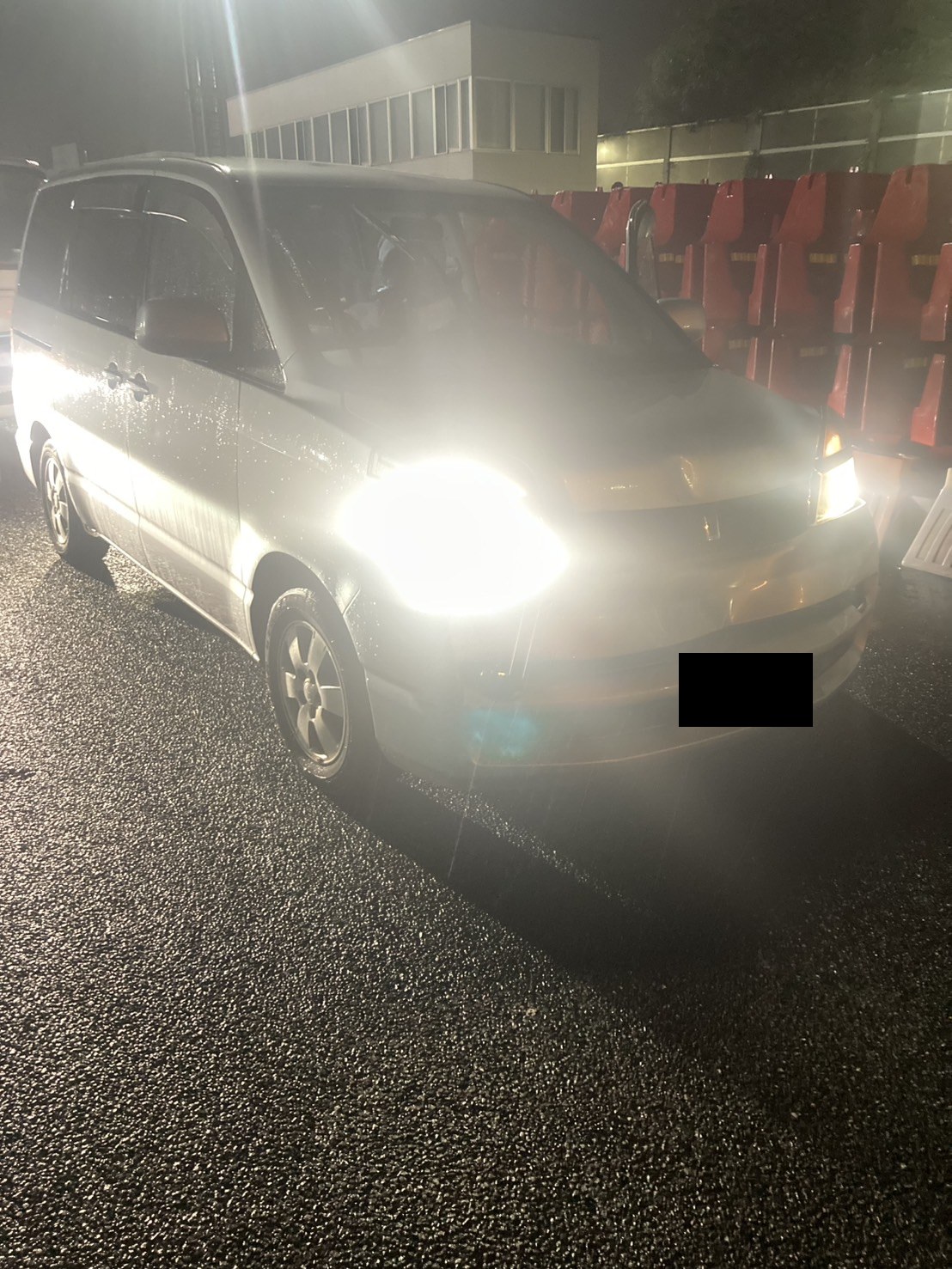 雨の夜、ヘッドライトを点灯したまま停車したミニバンを左前方から見た様子（ナンバープレートはマスク処理）