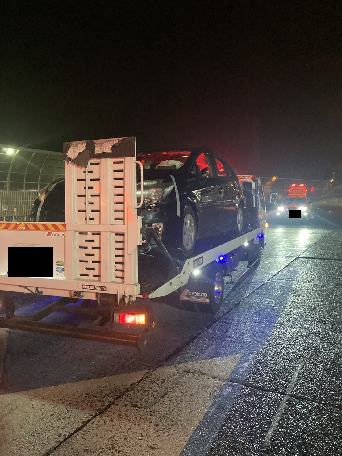 車両を載せた積載車を夜間に斜め後方から撮影