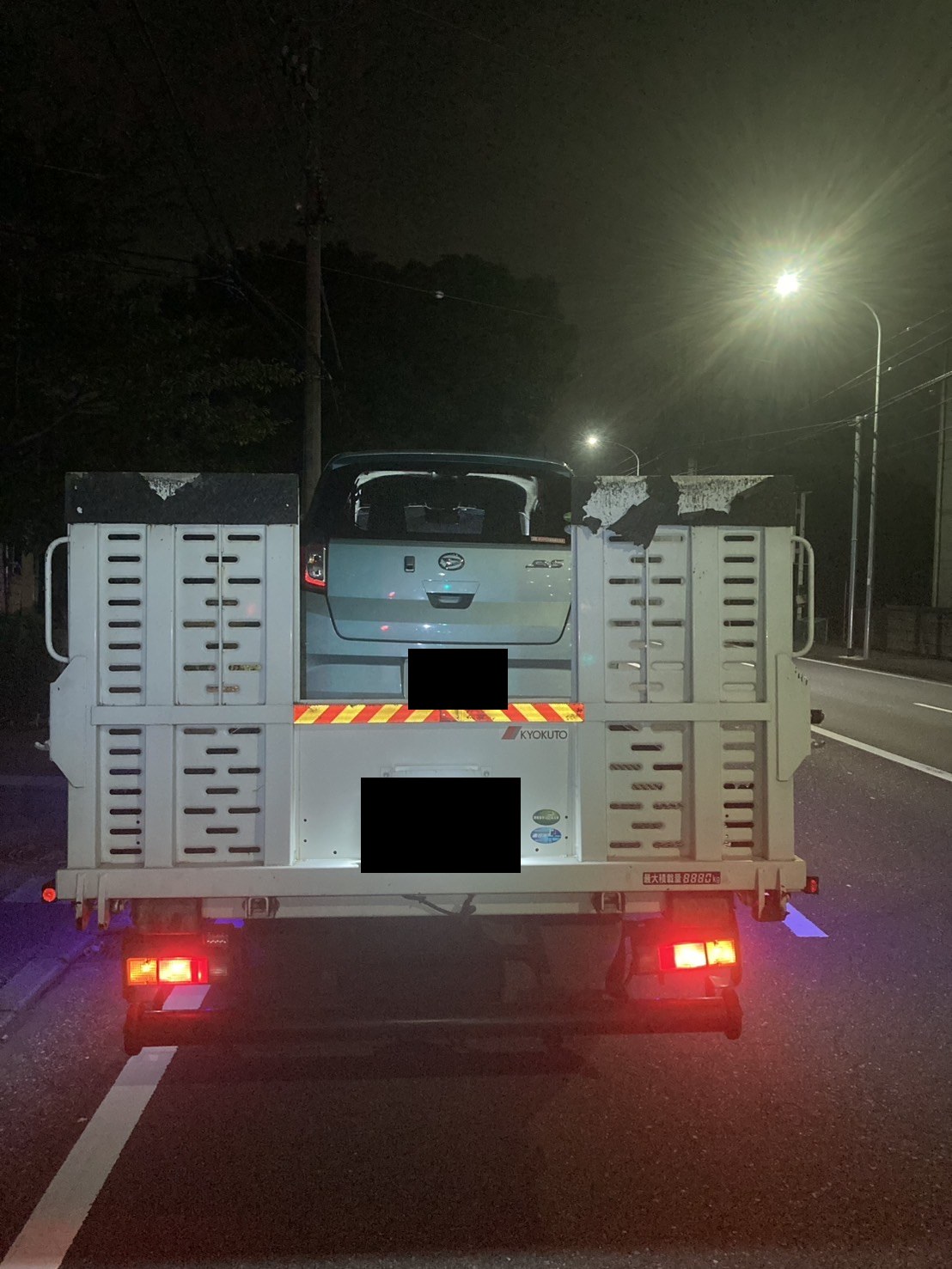 積載車の荷台に載せた軽自動車を後方から見た様子（お車と積載車のナンバープレートはマスク処理）