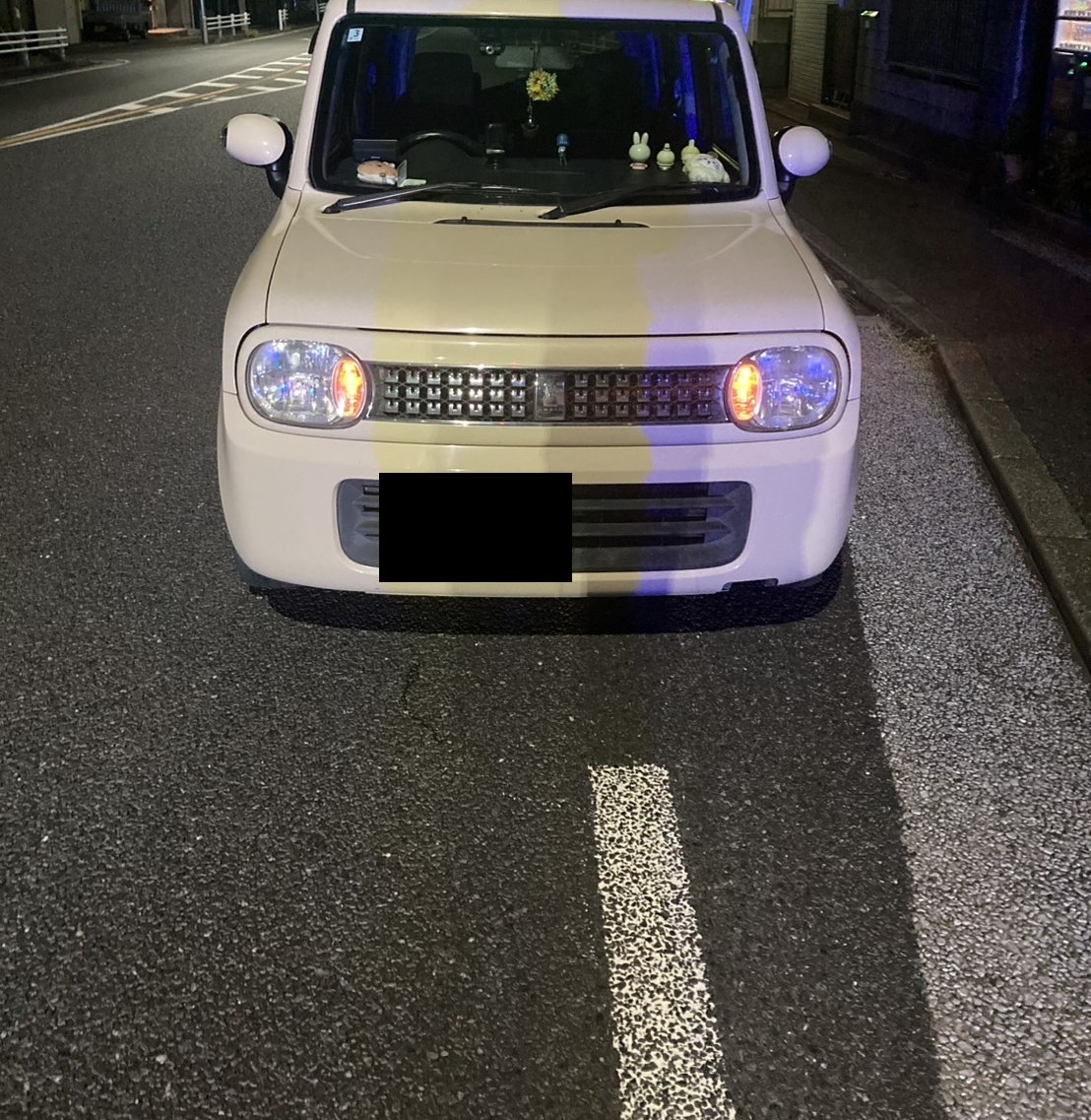 夜間、路上に停車した軽自動車を正面から見た様子（ナンバープレートはマスク処理）
