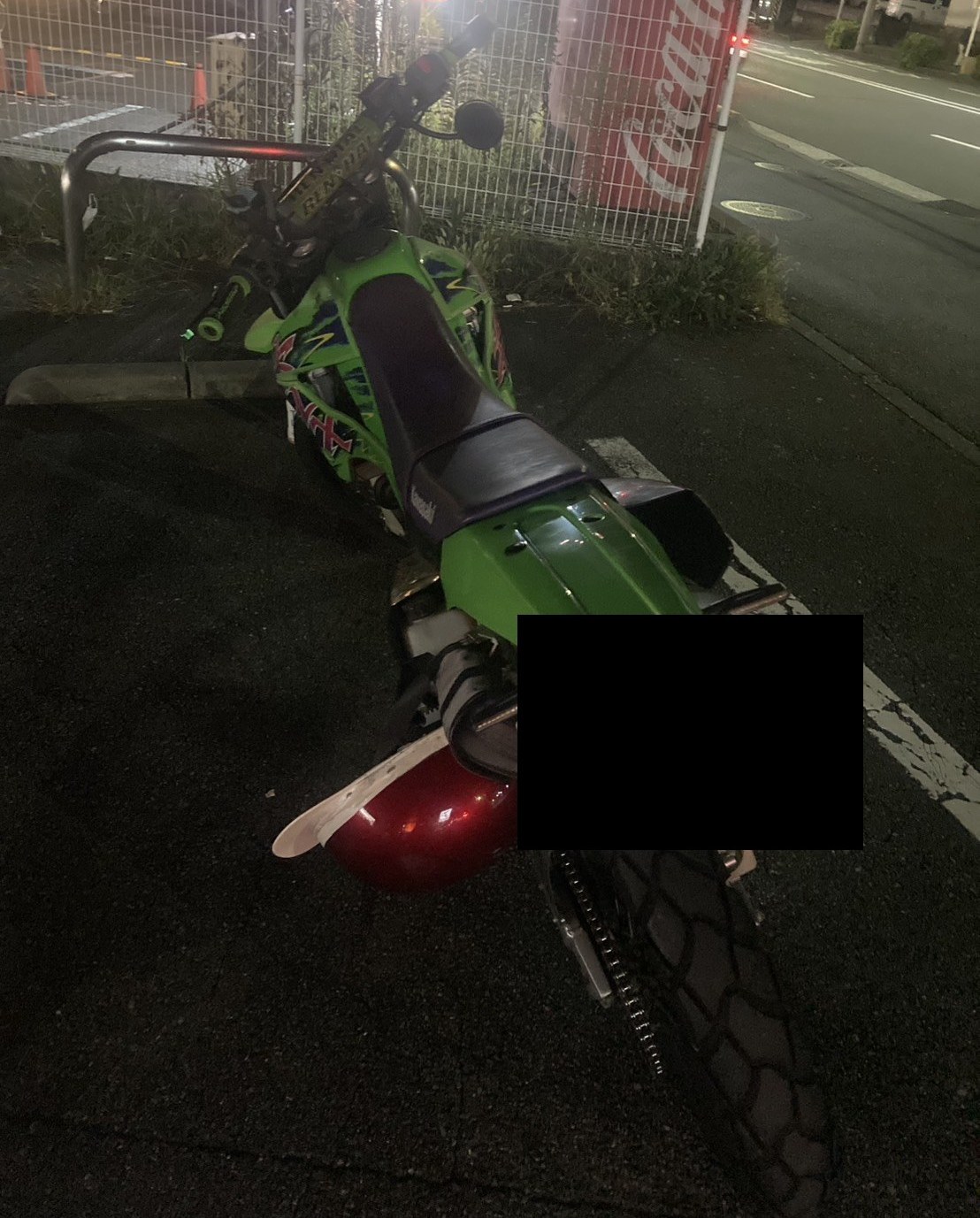 夜間、駐車場に停めた緑色のオフロードバイクを後方から見た様子（ナンバープレートはマスク処理）