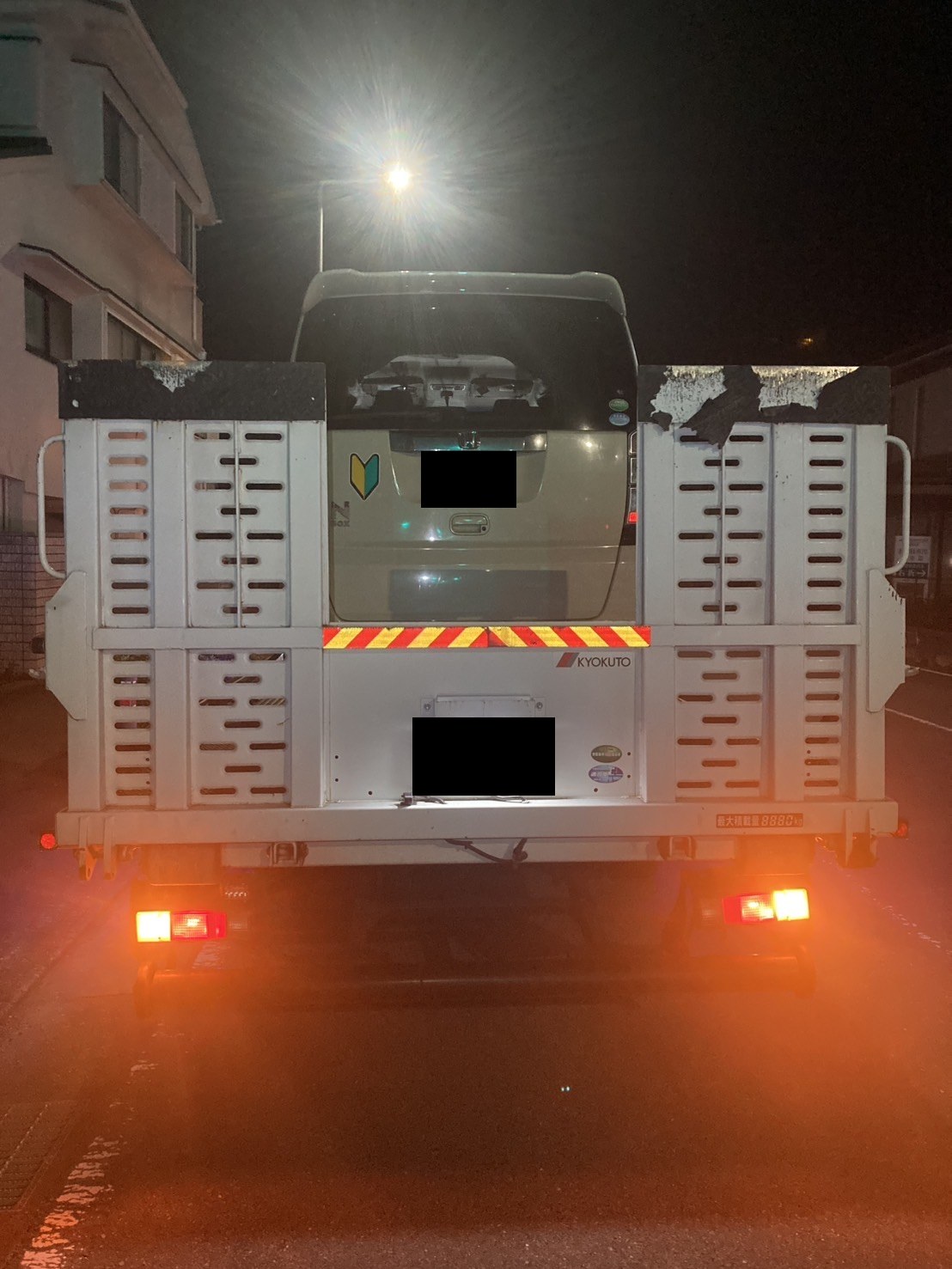 白い軽自動車を載せた積載車を後方から見た様子（お車と積載車のナンバープレートはマスク処理）