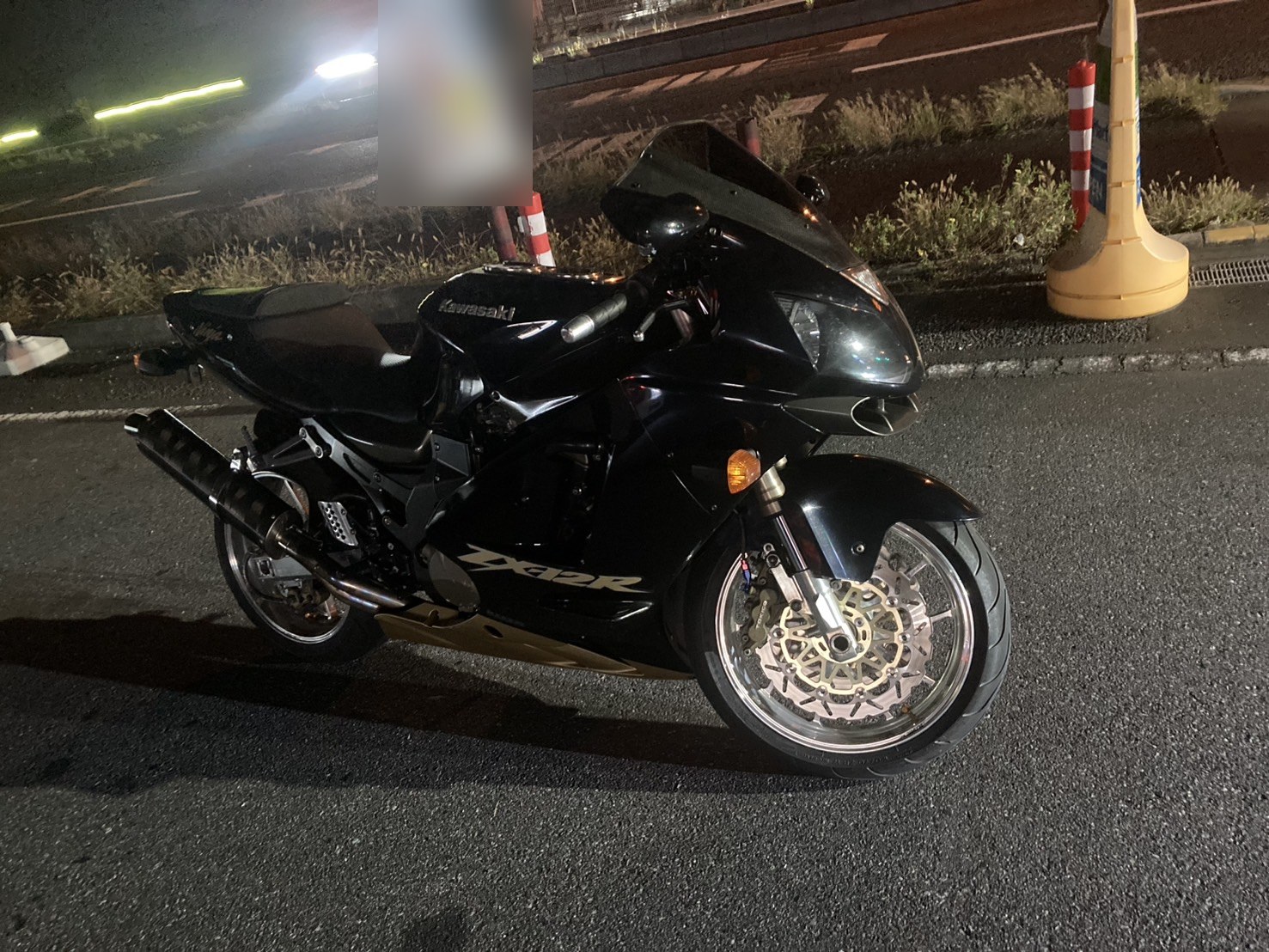 夜間、路肩に停めた黒い大型バイクを横から見た様子